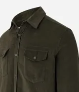 Camisa de hombre color verde oscuro, confeccionada en terciopelo, con cuello clásico, manga larga y dos bolsillos frontales con solapa y botón. Cierre frontal con botones.