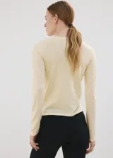 Chaleco de punto fino color amarillo claro, de corte recto, con cuello redondo, manga larga y cierre delantero de botonadura completa.