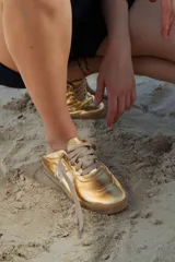 Zapatillas deportivas doradas con cordones color beige y suela de goma.