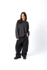 Buzo gris oscuro, estilo sweatshirt, con cuello redondo y terminaciones al corte en cuello, puños y cintura. Presenta un bordado en el frente.