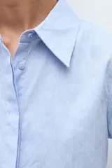 Camisa de manga larga color celeste, con cuello clásico y botones frontales.