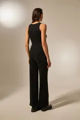 Pantalón negro de tiro alto, corte ancho y largo, confeccionado en tela con acabado brillante o con incrustaciones de strass.