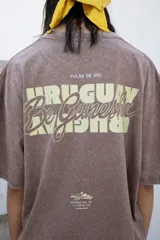 Remera marrón de corte oversize con estampa trasera con la palabra 'Uruguay' y logo delantero.