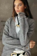 Cardigan de tejido suave en color gris, con escote en V, cierre frontal con botones y puños con detalle de botón.