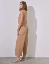 Mono color beige de crepe, marca Sharagano. Escote en V cruzado, sin mangas, con cintura elastizada y lazo de ajuste. Abertura central en espalda con cierre invisible y doble abotonadura. Bolsillos inclinados en delantera con aplique de botones.