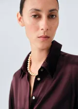 Camisa de seda de mora con acabado satinado, corte oversize, cuello camisero y cierre frontal de botones ocultos.