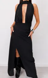 Vestido largo negro de fiesta, con escote halter pronunciado, detalle de cuello tipo choker con tiras colgantes y falda larga con abertura lateral.