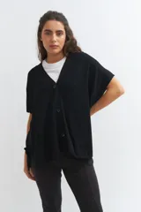 Cardigan negro de tejido de punto, corte amplio y mangas cortas.