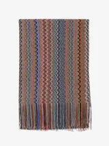 Chal de tejido de punto con el icónico patrón de zigzag multicolor característico de Missoni. Presenta un diseño alargado con terminaciones de flecos en los extremos, combinando tonos vibrantes y neutros.