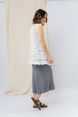 Chaleco tejido calado color crudo, con diseño artesanal, silueta relajada y largo a la cadera. Presenta terminación ondulada y detalle de lazo frontal.