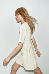 Vestido corto de punto rib color crema, con cuello redondo, manga corta abullonada y falda plisada.