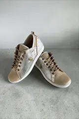 Championes de cuero de diseño artesanal, combinados en tonos plateado, dorado y natural. Presentan detalles pintados a mano por Carolina De Cunto, cordones al tono, suela de goma blanca y aplique metálico con logo en el lateral.