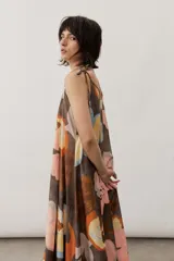 Vestido midi de tirantes ajustables con lazo en los hombros, escote en V y diseño amplio con estampado floral abstracto en tonos marrones, rosados, celestes y amarillos.