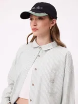 Gorra Rusty modelo Ottol de color negro, con visera curva que combina negro y verde, y bordado frontal en color blanco.