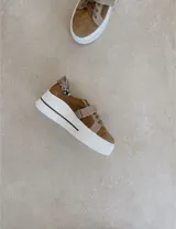 Sneakers de mujer estilo deportivo y urbano, color negro con detalles en beige claro. Presentan puntera y talón en negro, cuerpo principal en negro, y estrella lateral, cordones y tira de velcro en beige claro. La suela es blanca y el interior negro con la inscripción "LUCY IN THE SKY".