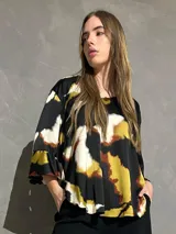 Blusa de manga larga acampanada con estampado abstracto en tonos negro, blanco, verde lima y caramelo, de corte holgado.
