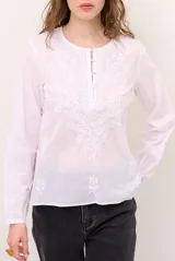 Blusa celeste de manga larga con delicados bordados florales en tono más claro en la zona del pecho y mangas. Presenta escote en V y puños elásticos abotonados.