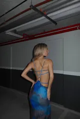 Vestido largo ajustado al cuerpo, con estampado abstracto en tonos azules, negro y rojo. Presenta tirantes finos y recortes laterales que dejan ver la piel.