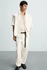 Pantalón de calce relajado confeccionado en tejido de viscosa y yute color tostado. Presenta cintura elástica ajustable con cordón, bolsillos laterales, bolsillos traseros de vivo y cierre frontal con cremallera y botón.