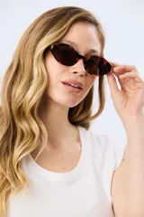 Lentes de sol polarizados con armazón ovalado de carey en tonos marrones y cristales oscuros.