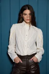 Camisa de algodón con estampado de rayas verticales finas, cuello alto con detalle de encaje broderie, cierre frontal con botones y mangas con frunces en los hombros y detalles de encaje.