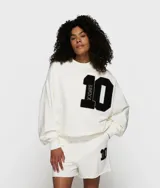 Suéter de felpa de algodón color blanco roto, de corte oversize y cuello redondo. Presenta un gran parche aplicado en el pecho con el número '10' en negro, con la palabra '10DAYS' verticalmente en el lado izquierdo del número.