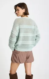 Sweater de punto calado color verde menta, con cuello redondo y diseño de rayas horizontales texturizadas, de mangas largas y corte holgado.