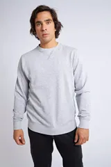 Buzo clásico de cuello redondo y manga larga, en color gris melange. Presenta un ajuste regular y un logo bordado con detalle en goma en el pecho.