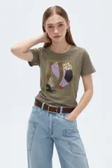 Remera de algodón de manga corta, color verde militar, con cuello redondo, corte ajustado al cuerpo y estampado frontal artístico de estilo ilustrado.