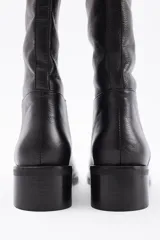 Bota de caña alta confeccionada en cuero vacuno, con taco cuadrado bajo y punta redondeada.