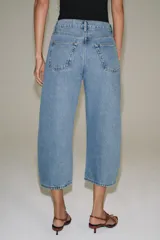 Jeans capri balloon leg de tiro medio en color celeste, con trabillas para cinto, bolsillos delanteros y traseros, y cierre frontal con botón y cremallera.