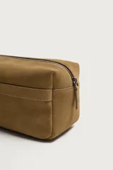 Neceser rectangular de piel con acabado serraje en color marrón, con compartimento principal con cierre de cremallera y asa lateral de mano.
