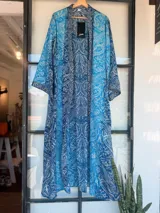 Kimono largo de tela estampada con motivos abstractos en tonos azules, verdes y beige. Diseño de manga ancha y corte recto, sin cierres.
