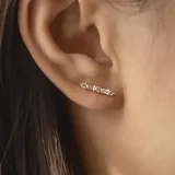 Par de aros largos plateados con forma lineal, con tres brillantes redondos y dos rectangulares.