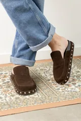 Zuecos tipo mule de cuero gamuzado negro, con plataforma forrada y detalle de tachas plateadas en el contorno. Presentan una plantilla con el logo bordado.