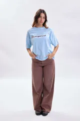 Remera de corte boxy color celeste, con mangas cortas y cuello redondo. Presenta la palabra 'Buongiorno' bordada en el frente en color marrón.