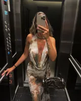 Vestido largo de microtul con estampado abstracto en tonos marrones y blancos, escote halter pronunciado, espalda descubierta y aberturas laterales en la cintura.