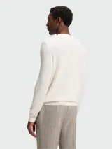 Buzo de punto fino con cuello redondo y mangas largas, confeccionado en lana virgen. Presenta un diseño minimalista con el logo de la marca bordado sutilmente en el pecho.