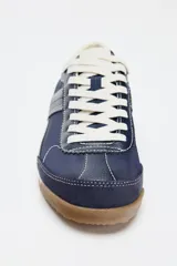 Zapatillas deportivas de color azul marino, con cordones blancos, suela color crema y detalles en cuero sintético blanco en el talón.