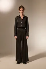 Pantalon de vestir de corte ancho y tiro alto, confeccionado en tela de viscosa con acabado satinado. Presenta cintura elástica y diseño fluido.