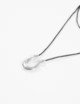 Collar con cordón negro y dije irregular plateado.