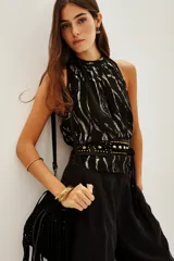 Top sin mangas de cuello alto con frunces, confeccionado en tela negra con estampado de cebra en hilo metalizado. Posee forro interior.