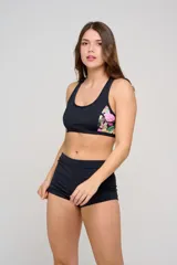 Top deportivo negro con diseño de espalda nadadora y breteles anchos fijos. Cuenta con inserciones de tela con estampado animal print colorido en los laterales.