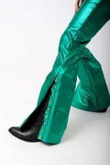 Pantalón largo de cuero sintético verde metalizado, de corte acampanado con aberturas laterales con botones a presión.