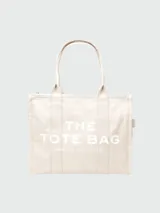 Bolso tipo tote de lona color beige, con diseño estructurado, doble asa superior y cierre superior con cremallera. Presenta el nombre del modelo y la marca estampados en contraste en la parte frontal.