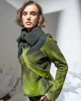 Chaqueta de lana merino afieltrada color verde camuflaje, de corte desestructurado, con cuello alto y tiras para atar en la cintura o cruzar en el cuello.