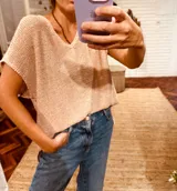 Remera tejida en lurex color rosa con detalles dorados y contornos en crochet, de mangas cortas y cuello en V.