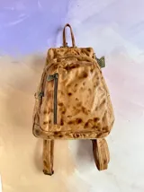 Mochila Lucy de cuero color terra con efecto desgastado, múltiples bolsillos externos con cierre y herrajes de metal envejecido.