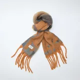 Bufanda de tejido suave con diseño jaspeado en tonos naranja y azul, terminada con flecos en los extremos y etiqueta de marca cosida.
