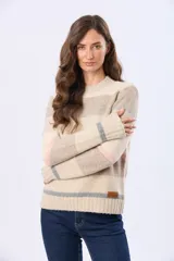 Buzo de tejido de punto con diseño de rayas horizontales en tonos neutros, beige y detalles en rosa y gris. Presenta cuello redondo, mangas largas y terminaciones en rib acanalado en puños y ruedo. Incluye una pequeña etiqueta de cuero sintético en el lateral inferior.